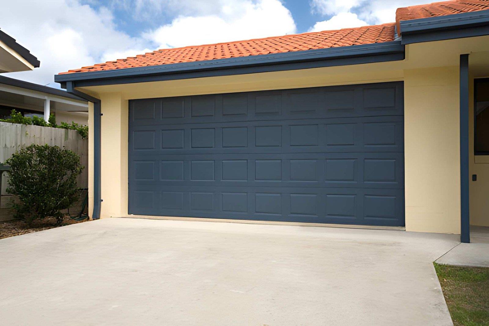 A modern house with a dark blue garage door and a concrete driveway.
