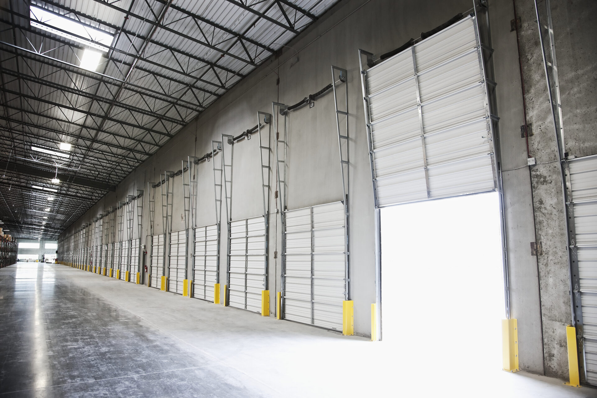 Row of commercial overhead loading-dock garage doors inside a warehouse